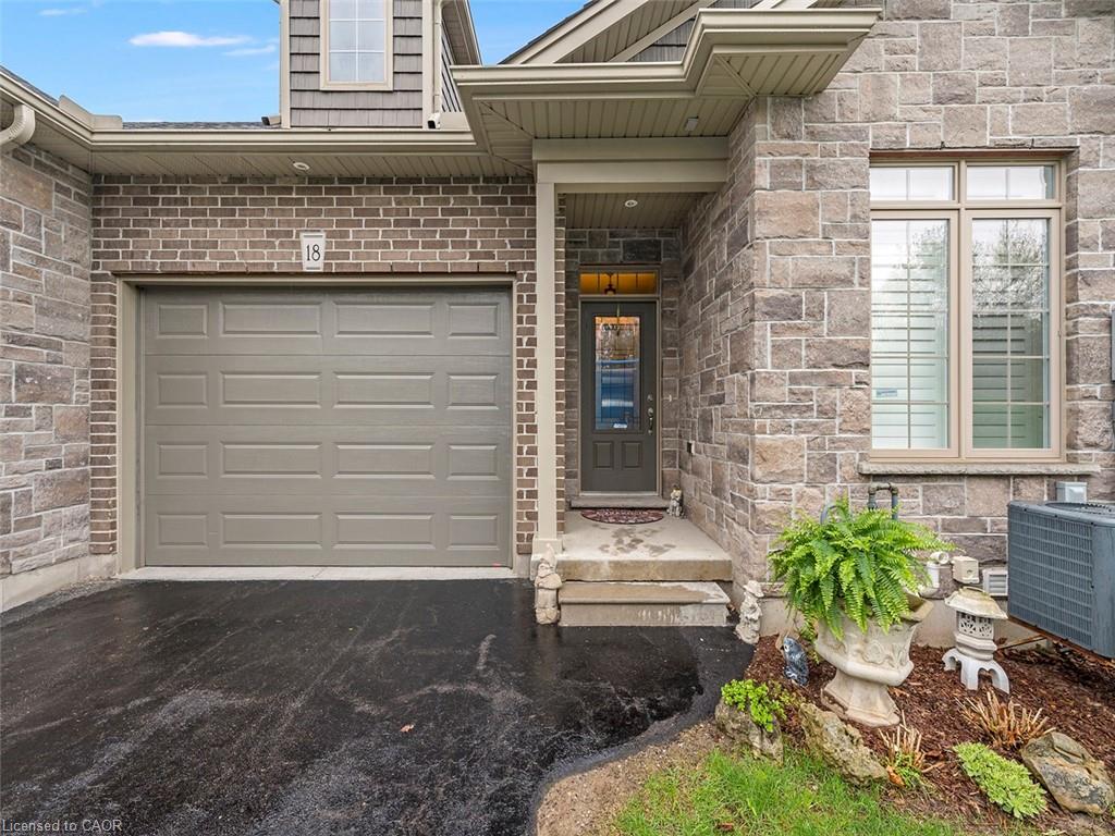 Stone and brick exterior with a single-car garage and asphalt driveway