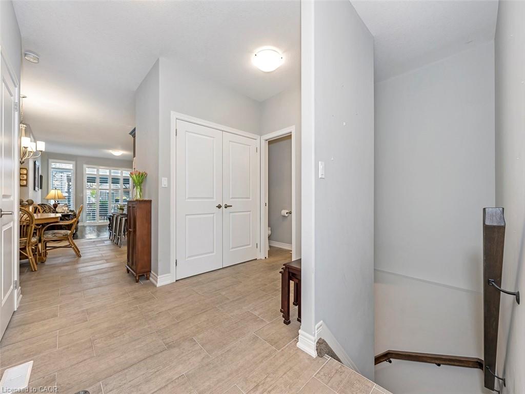 Entryway featuring wood-finish tile flooring, a double-door closet, and a partial staircase with wood railing