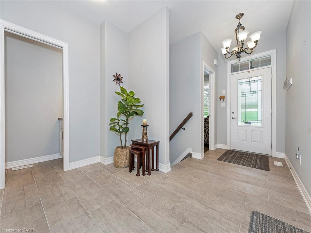 Entryway featuring light-toned tile flooring, a decorative front door with clear glass inserts, and a staircase with a dark wood handrail