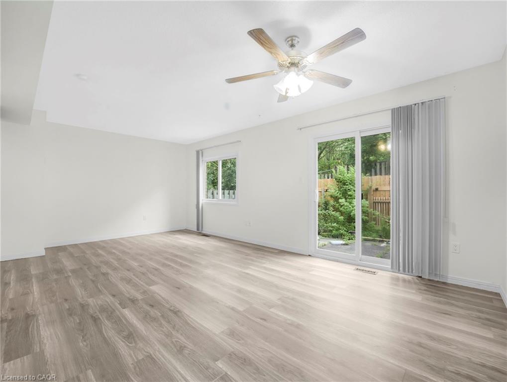 Spacious room featuring wood-finish flooring, white walls, and a ceiling fan