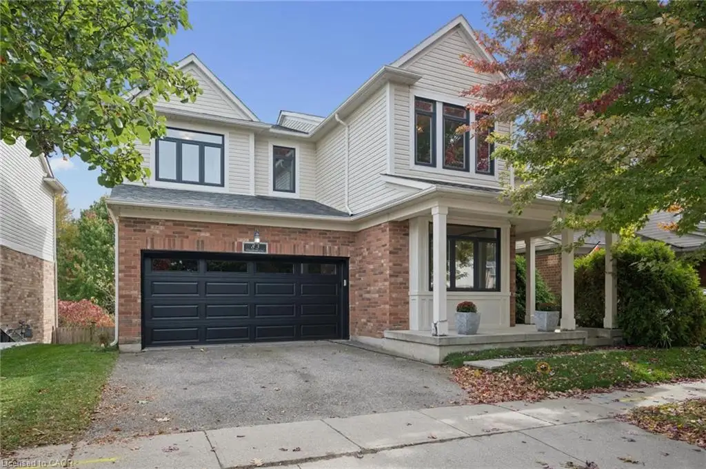 Two-story residence featuring a combination brick and horizontal siding exterior, a covered front porch with columns, and an attached two-car garage with black paneled doors