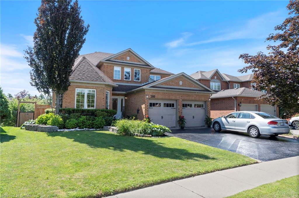 Two-story brick exterior with a two-car garage, asphalt driveway, and a manicured lawn