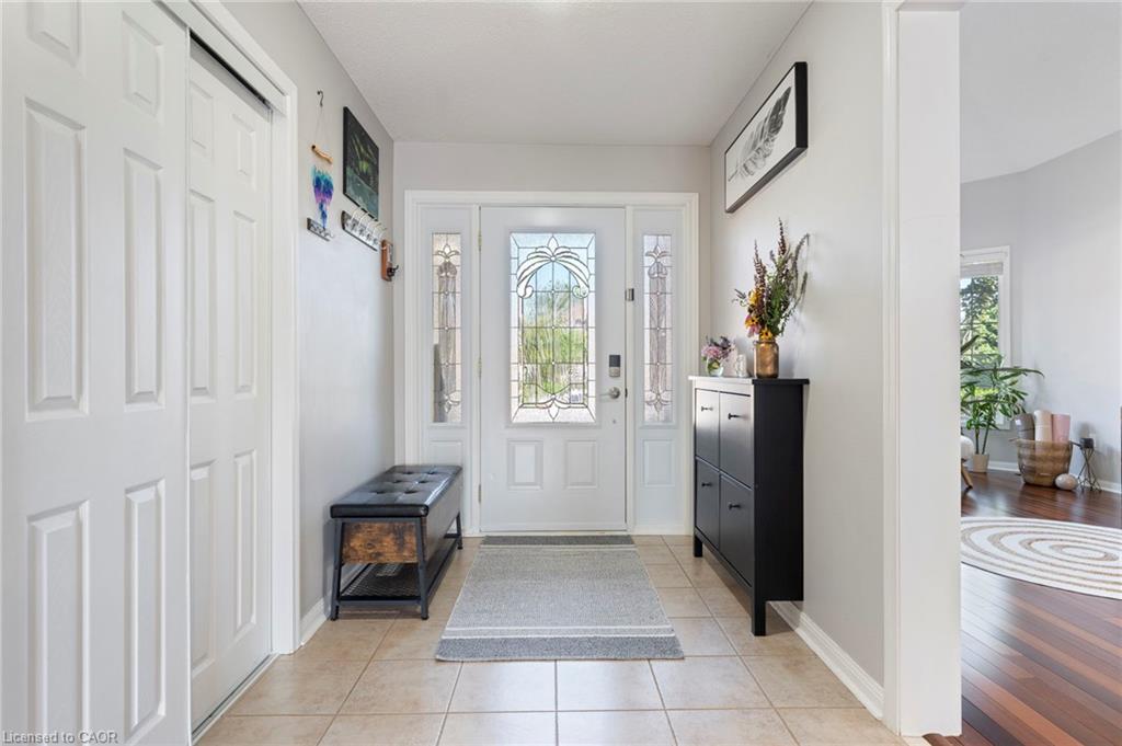 Entryway featuring tiled flooring, a white paneled entry door with decorative glass inserts, and white bi-fold closet doors