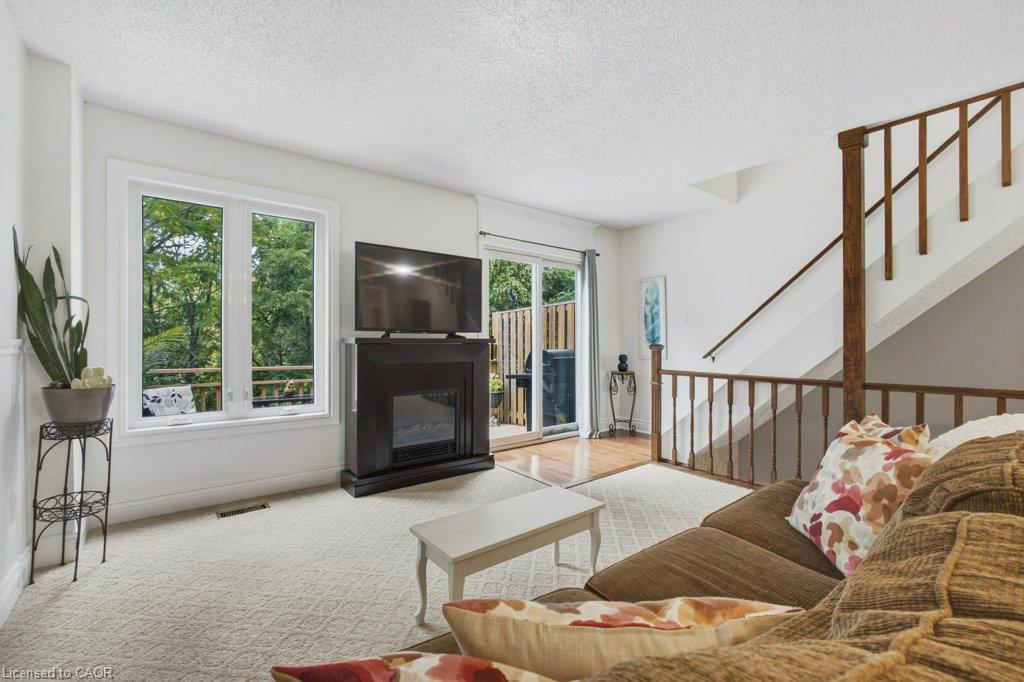 Carpeted living area featuring a built-in fireplace, large windows, and direct access to an outdoor space via sliding glass doors