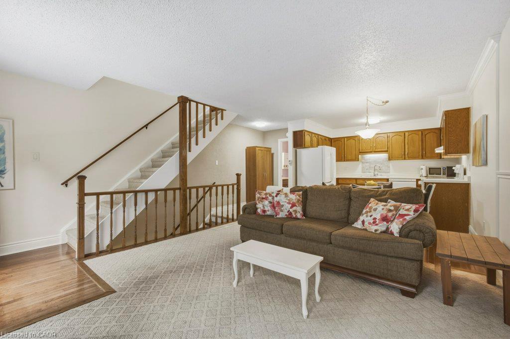 Open-concept living area featuring a gray upholstered sectional sofa, wood-finish flooring throughout, and abundant natural lighting from vaulted ceilings