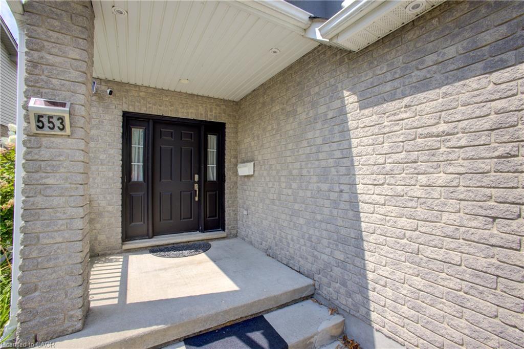 Gray brick exterior with a dark paneled entry door, sidelight windows, and a concrete entry porch