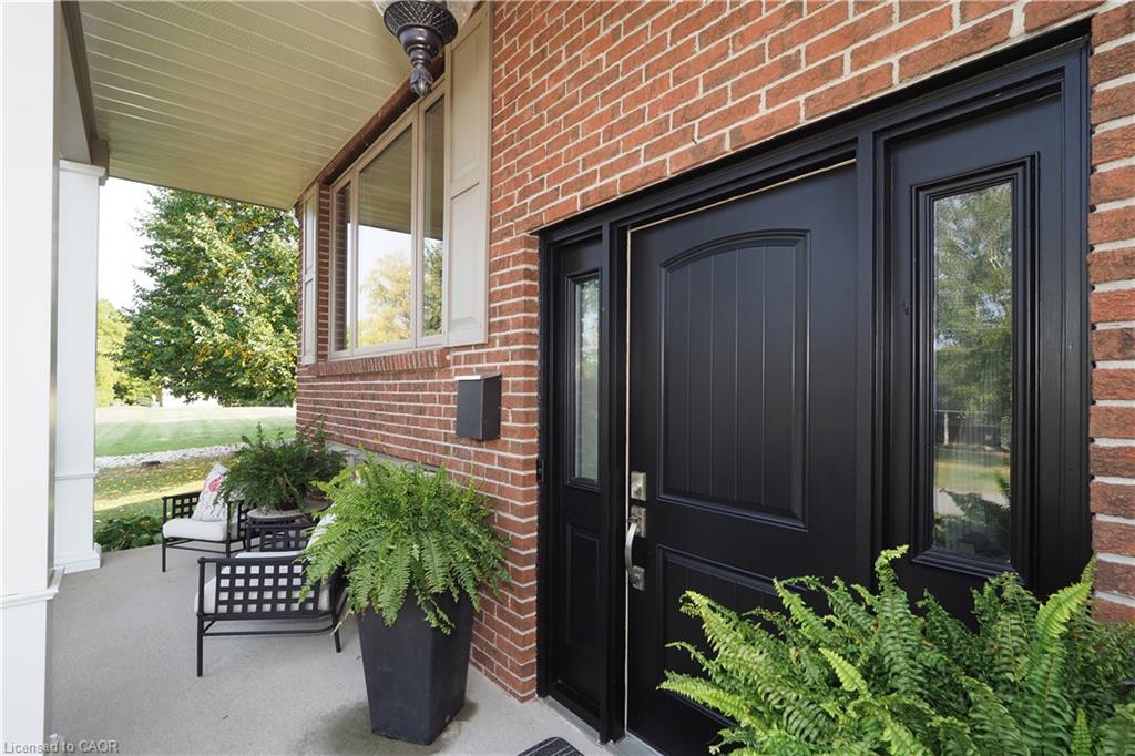 Brick facade with a covered porch, featuring a dark panel-style entry door, side-lite windows, and an overhead light fixture