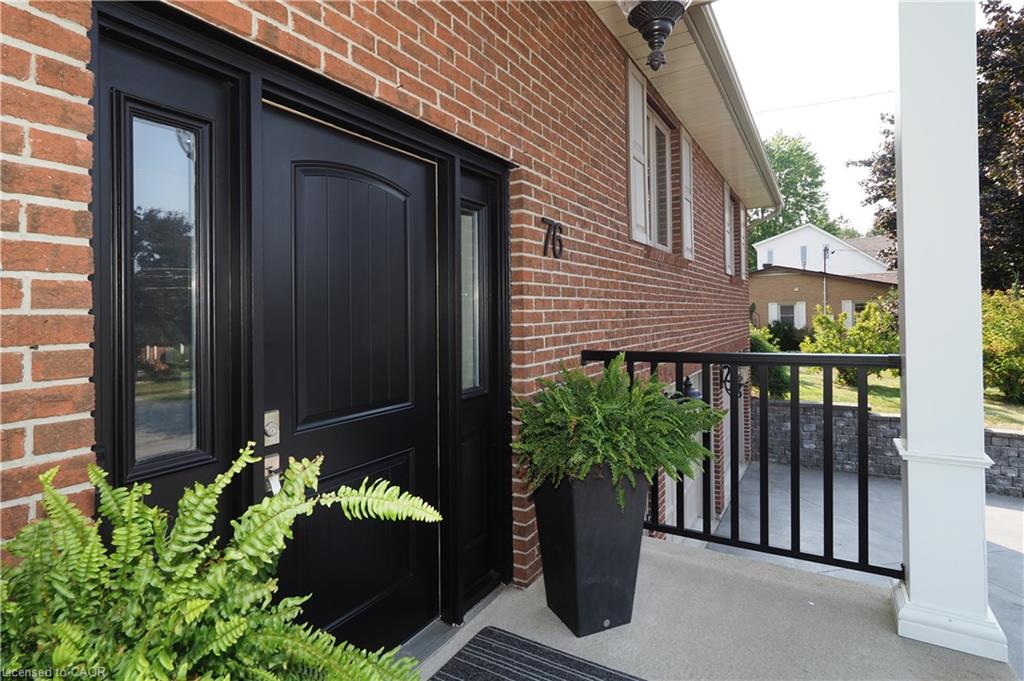 Brick exterior with a black paneled front door, sidelight windows, and a black metal railing