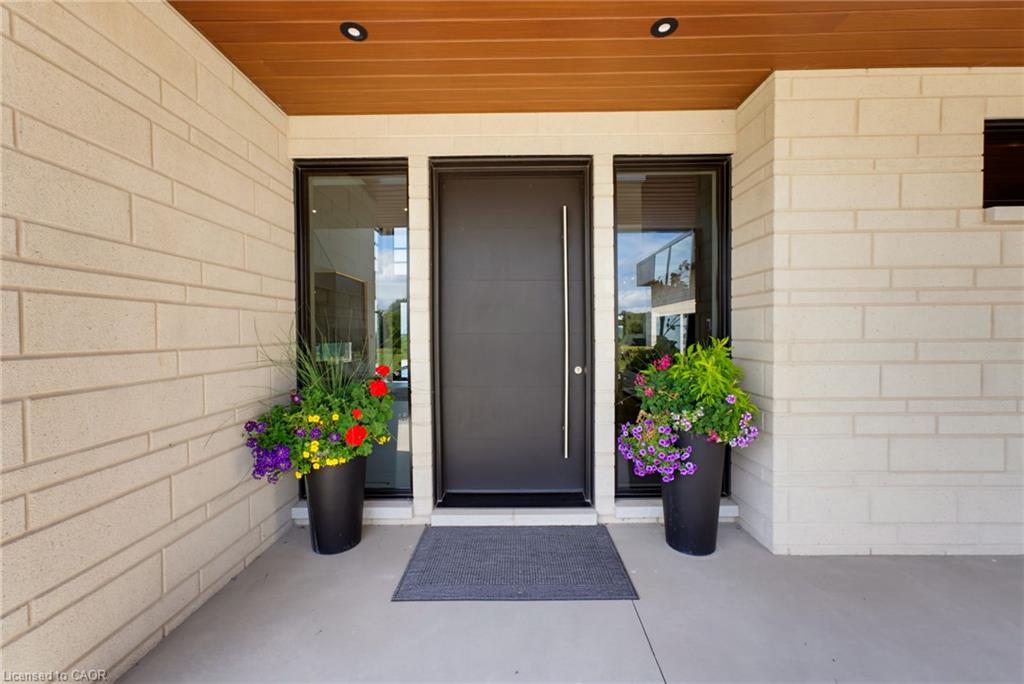 Welcoming entry featuring a dark-finish front door with sidelights, flanked by black planter vessels with seasonal flowers