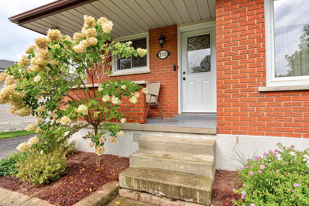 Brick exterior with white trim, concrete steps, and a covered entry