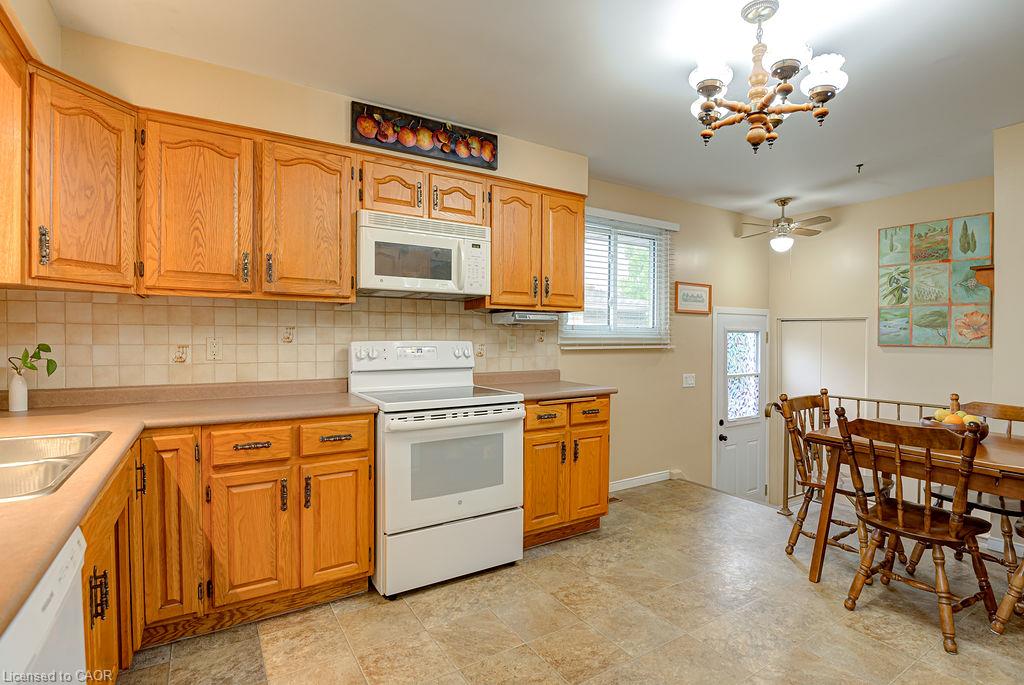 Wood cabinetry, tile backsplash, built-in microwave and ceiling fan