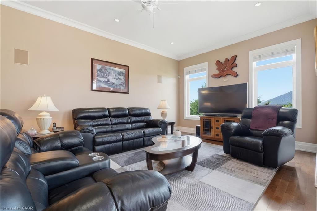 Recessed ceiling lighting, crown molding, multiple windows, built-in wall speakers, and wood-finish flooring