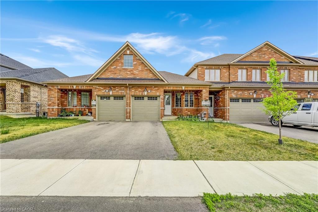 Brick exterior featuring a gabled roofline, covered entry, and two attached garage bays with panel doors