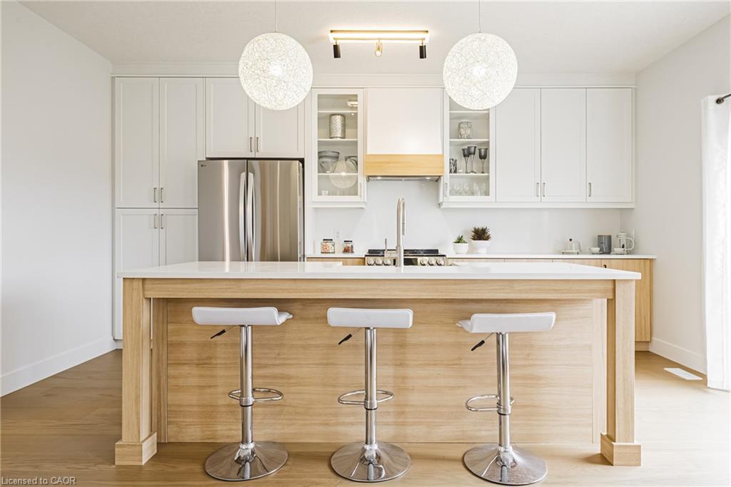 Kitchen featuring a central island with a light wood finish, white countertops, stainless steel appliances, white cabinetry, and wood-finish flooring