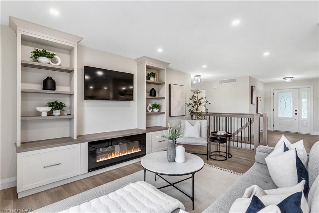 Integrated built-in shelving, electric fireplace with media console, wood-finish flooring, recessed lighting, and double entry doors