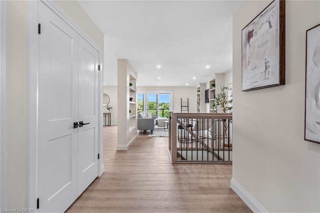 Wood-finish flooring throughout, white paneled doors with black hardware, recessed lighting, and a staircase with a wood handrail and black metal balusters