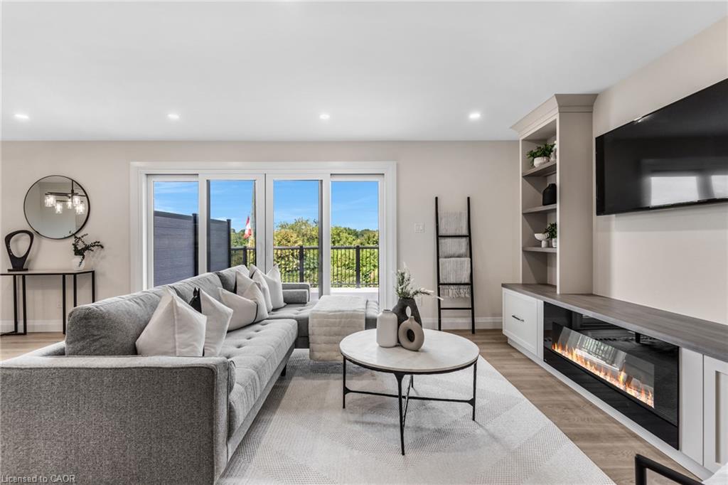 Bright living area featuring wood-finish flooring, recessed lighting, and a built-in media console with an electric fireplace