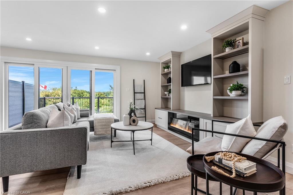 Spacious living area featuring large east facing sliding glass doors, built-in shelving, a modern electric fireplace, and recessed lighting