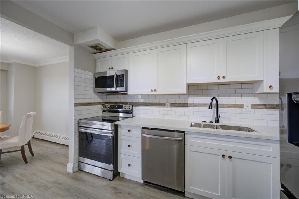 Modern kitchen featuring white shaker cabinetry, stainless steel appliances, a subway tile backsplash with accent band, a double basin sink, and a matte black gooseneck faucet