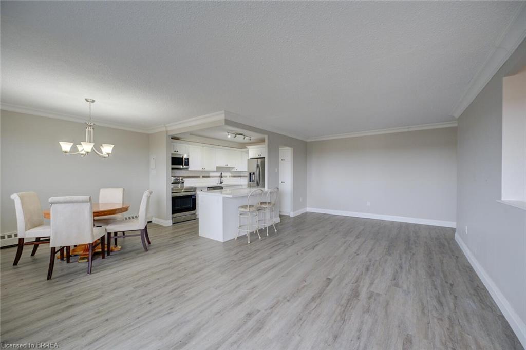 Open-concept living space featuring wood-finish flooring and crown molding