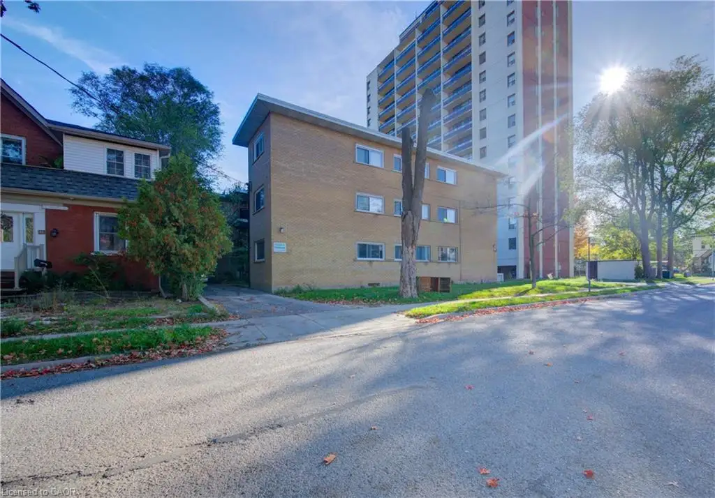 Brick exterior apartment building with multiple windows and a paved driveway