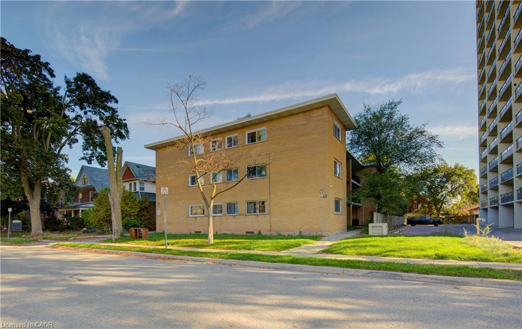 Three-story exterior featuring brick construction, multiple windows, and a landscaped green space