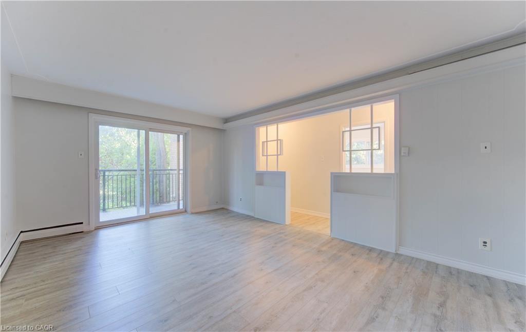 Spacious room featuring wood-finish flooring, light-colored walls, and a sliding glass door leading to a balcony with metal railings