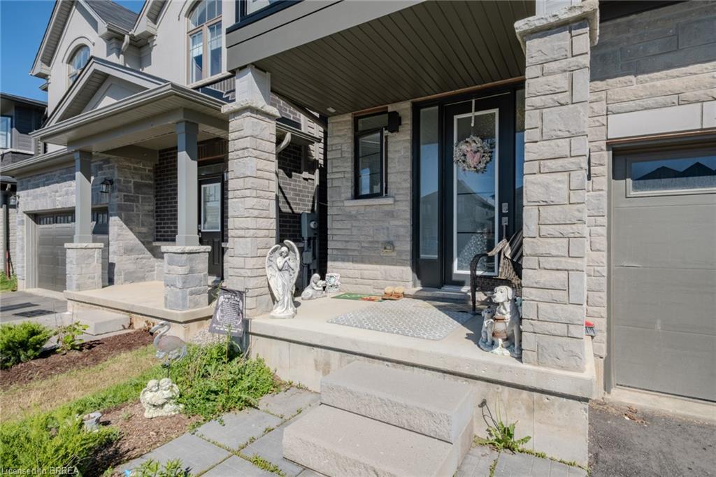 Stone facade with covered front porch, featuring a dark-framed entry door with clear glass panels