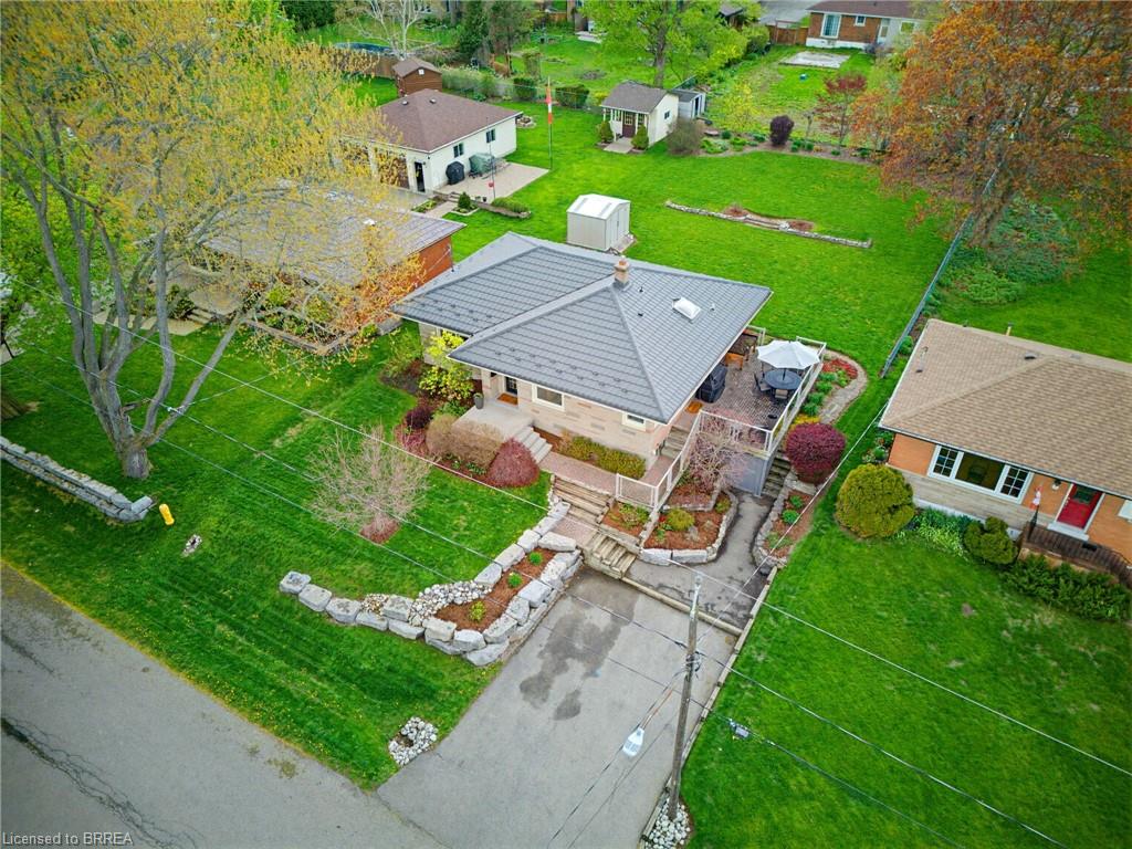 Aerial perspective highlighting a residential property with a multi-level deck, a metal roof, and a paved driveway