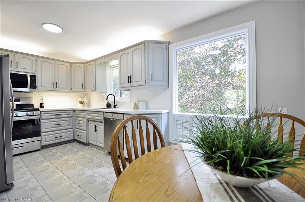 Kitchen featuring light gray cabinetry, stainless steel appliances, white countertops, and a tile backsplash