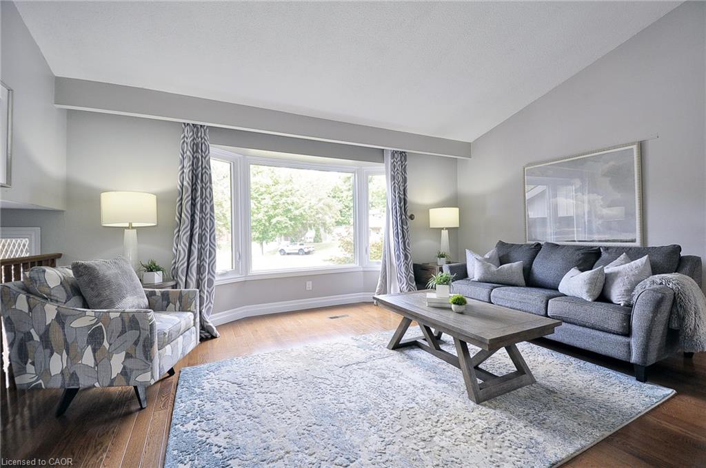 Vaulted ceiling, bay window, wood-finish flooring, recessed lighting, and neutral wall tones
