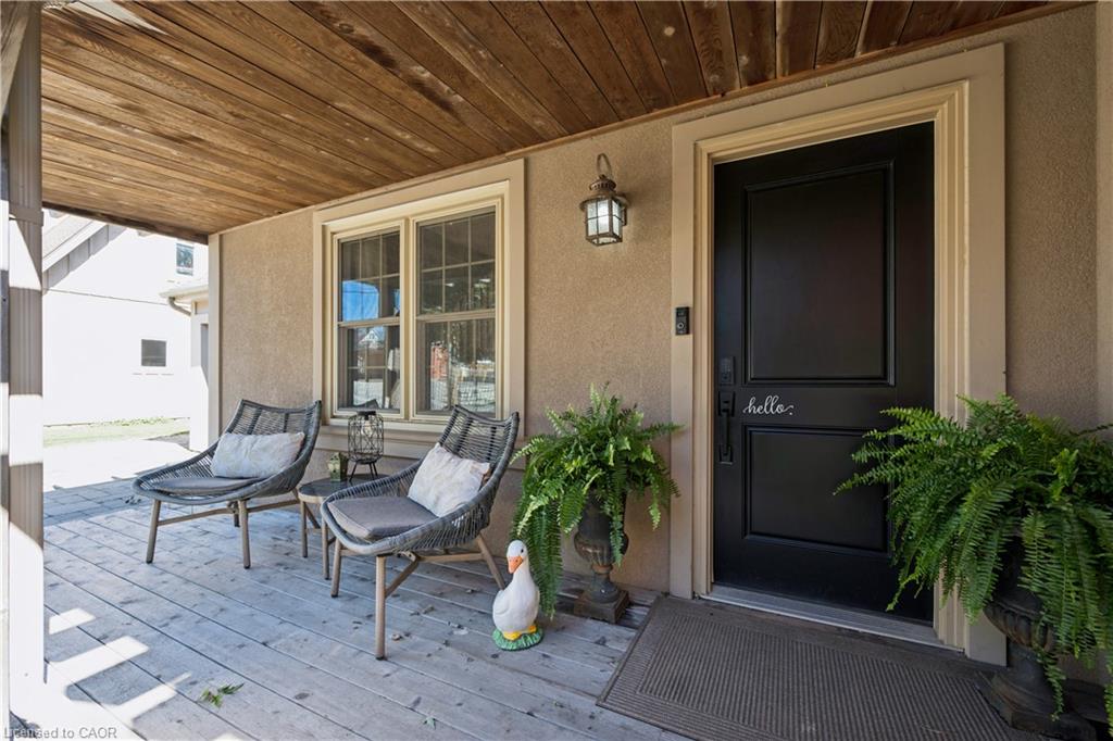 Covered front porch featuring a wood-plank ceiling, wood-finish flooring, and a paneled entry door