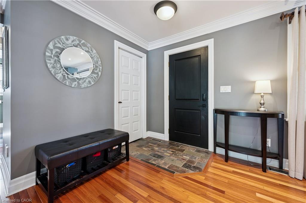 Hardwood flooring, slate tile entry, crown molding, white trim, and a paneled door