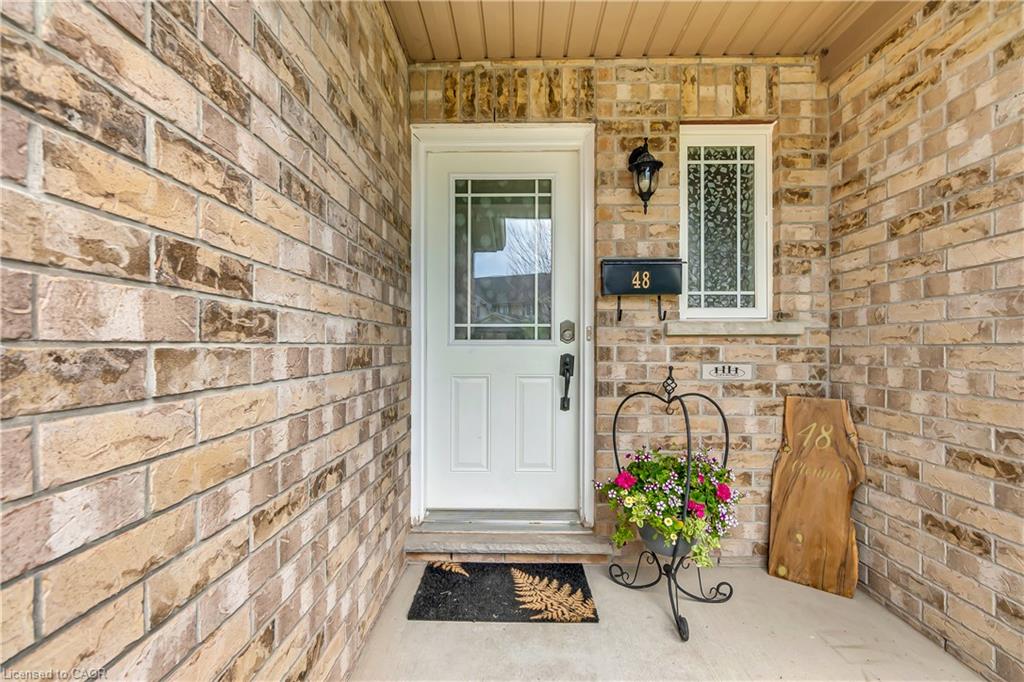 Brick exterior with a covered front porch and a white entry door featuring decorative glass
