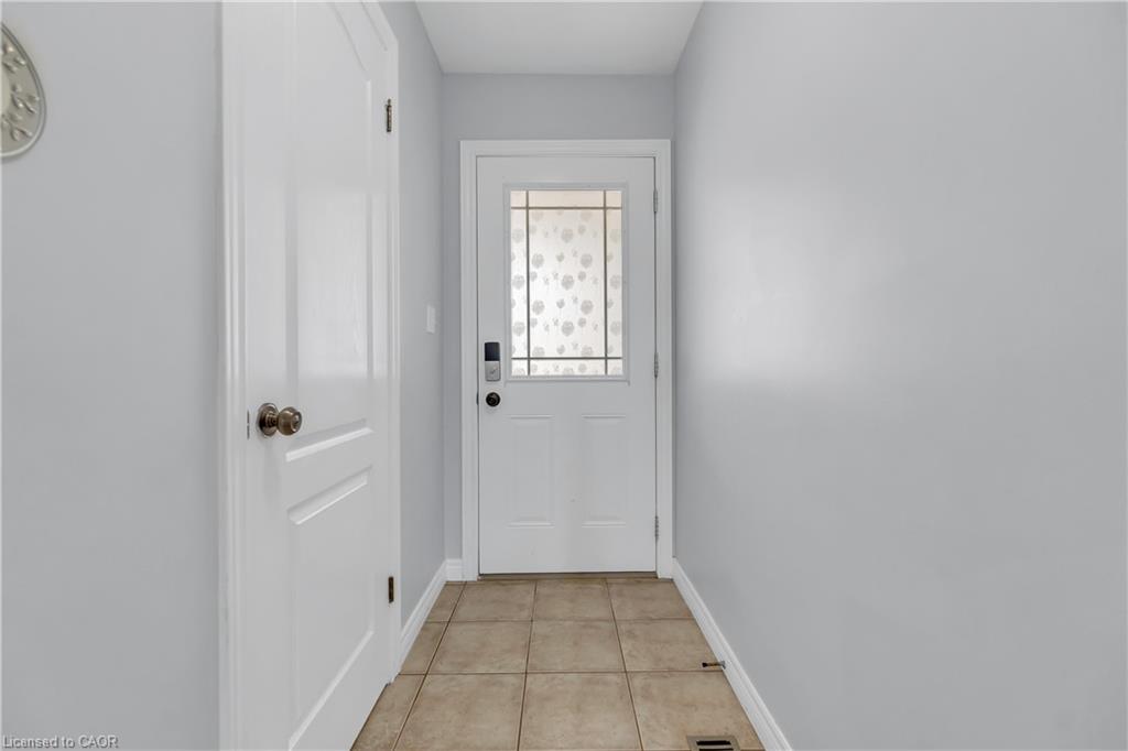 Entryway featuring a white paneled door with patterned glass, a second white paneled door, light gray walls, and tile flooring