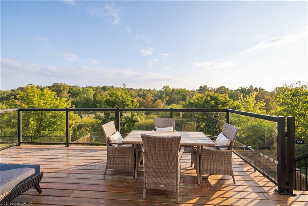 Expansive outdoor deck featuring wood flooring, a glass railing system, and stairs