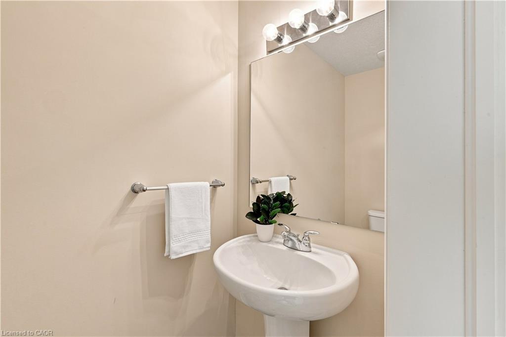 Pedestal sink with chrome faucet, large vanity mirror, and overhead vanity lighting