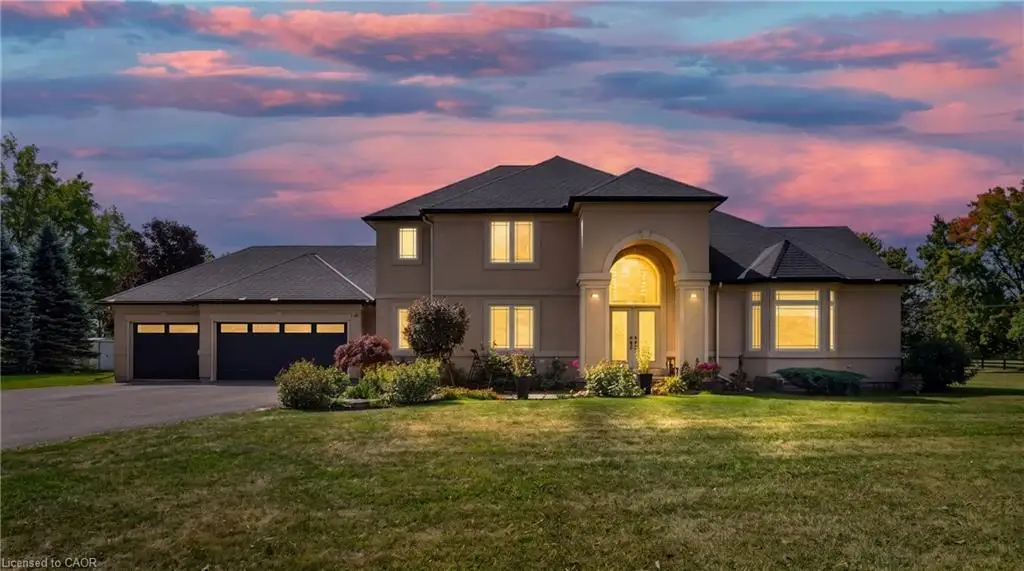 Stucco exterior featuring a prominent arched entryway, multi-car garage, and manicured landscaping