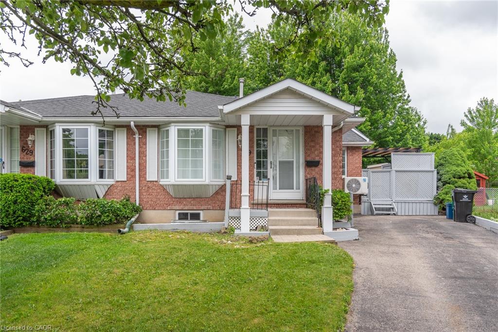 Brick exterior featuring dual bay windows with white trim, a covered porch entry, and an asphalt driveway