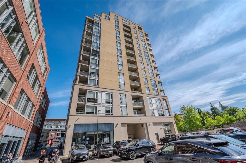 Multi-story building featuring a light-toned facade, multiple balconies, and ground-level commercial spaces