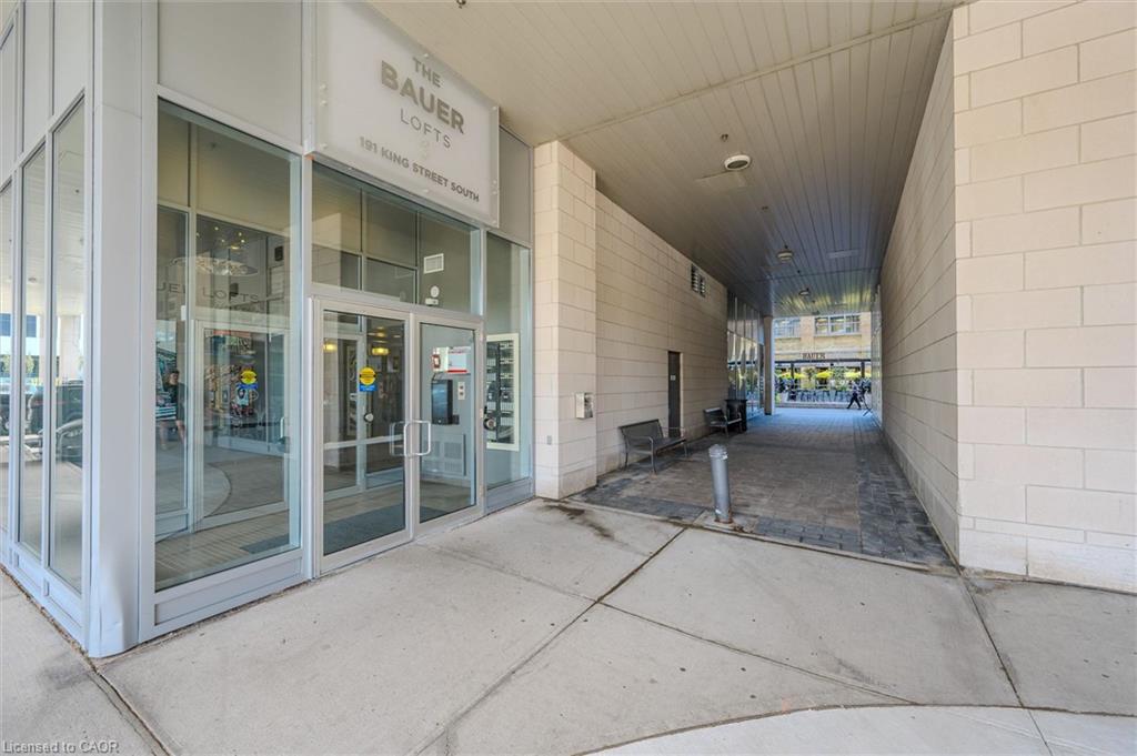Modern building entrance with extensive glass paneling, aluminum-framed doors, an overhead canopy, and a stone block facade