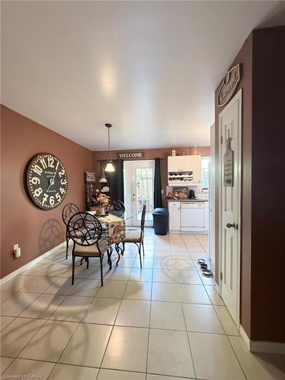 Tile flooring, pendant light fixture, white cabinetry, and white paneled door