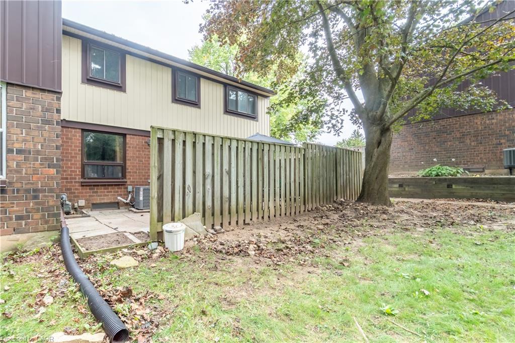 Exterior brick and siding combination, privacy fencing, concrete patio, mature tree, and grassy yard