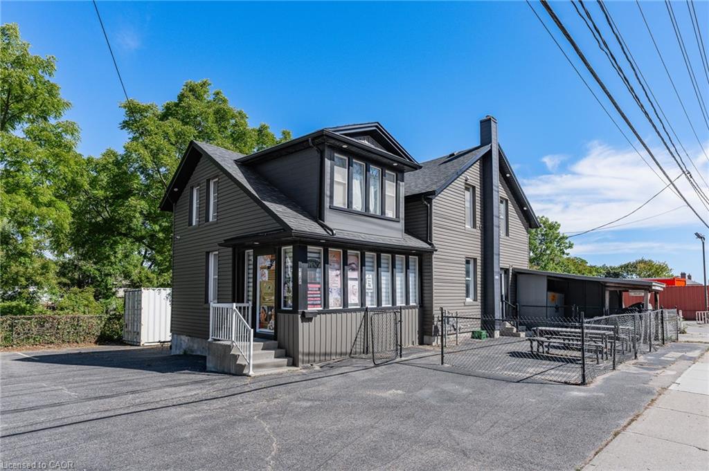 Modern residential architecture featuring a distinctive black exterior with mixed siding materials, large multi-pane windows with contemporary framing, and a gabled roofline