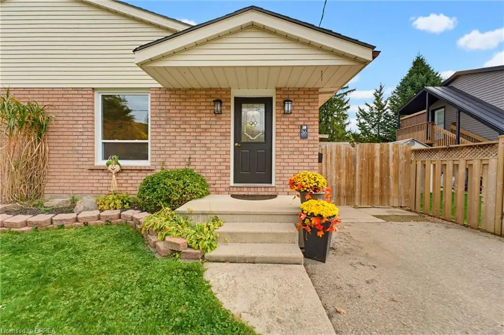 Exterior facade featuring brick masonry and horizontal siding, covered entryway with a concrete stoop, and wood-slat privacy fencing