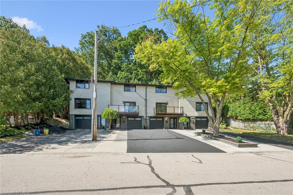 Multi-level stucco exterior with large windows, individual garage doors, and private balconies with glass railings
