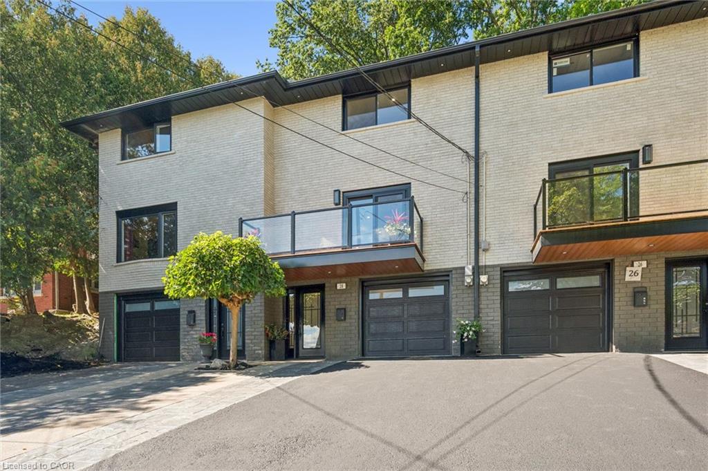 Modern townhome exterior featuring light-toned brick, dark-framed windows, and integrated single-car garages