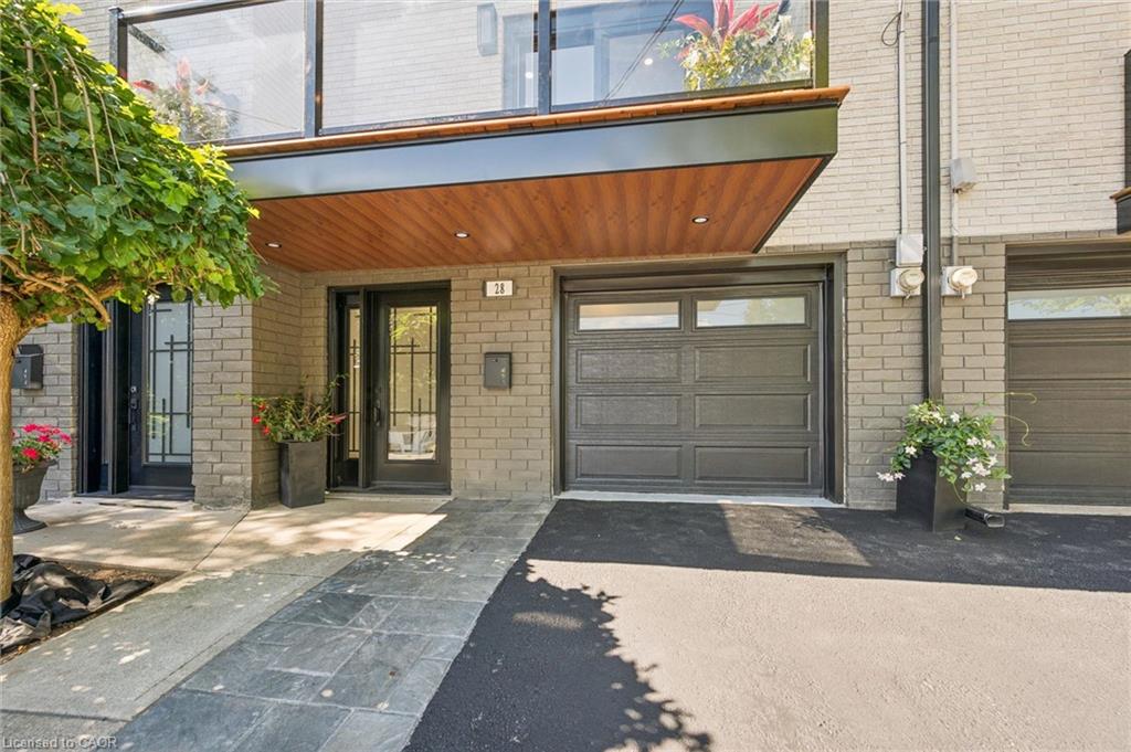 Light brick exterior with a wood-finish soffit, glass-panel entry door, dark garage door with windows, and a glass-paneled balcony
