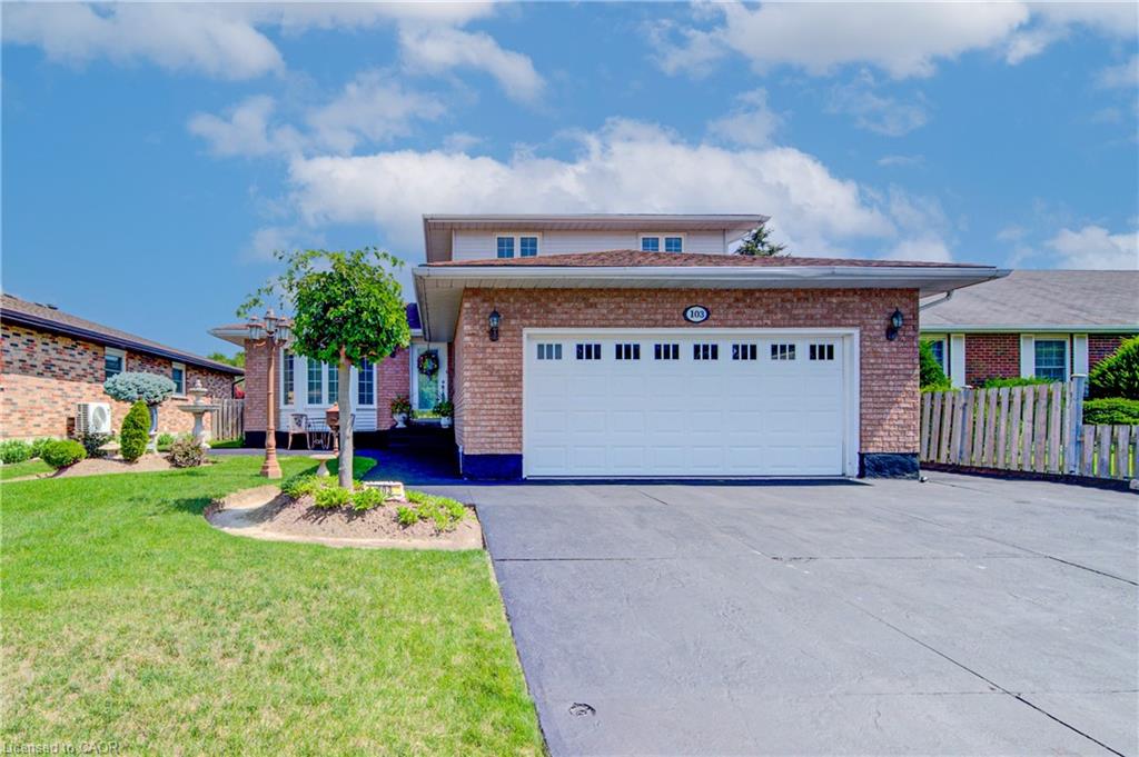 Brick exterior with an integrated garage, paved driveway, and established front landscaping