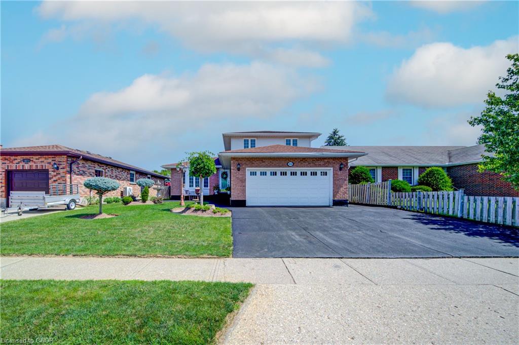 Brick exterior with an integrated two-car garage, expansive paved driveway, and established front landscaping